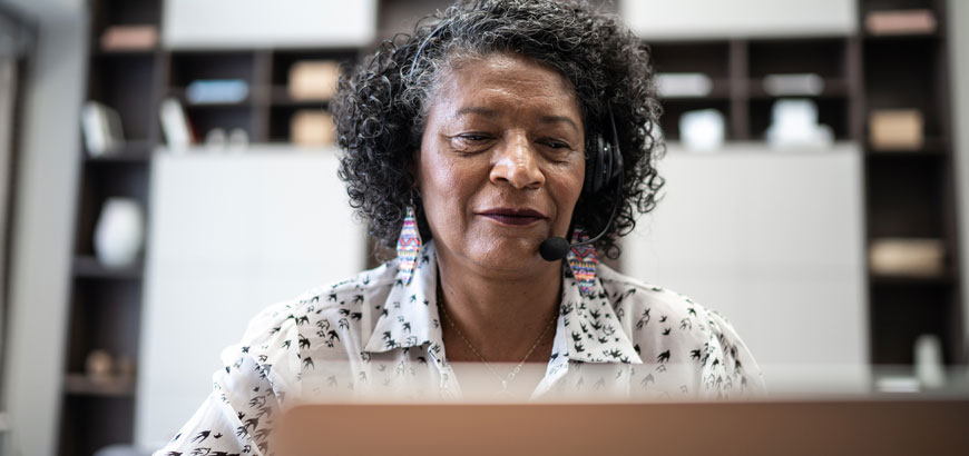 A woman sitting in front of a computer with a headset on