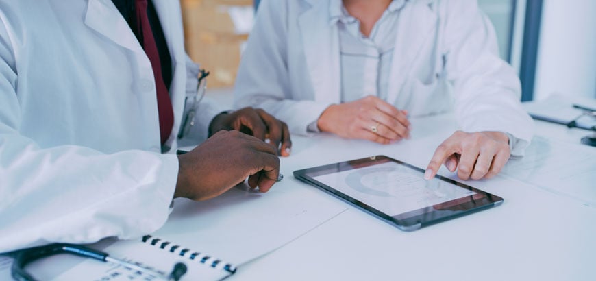 <span>Partial view of healthcare professionals reviewing information on tablet.  </span>