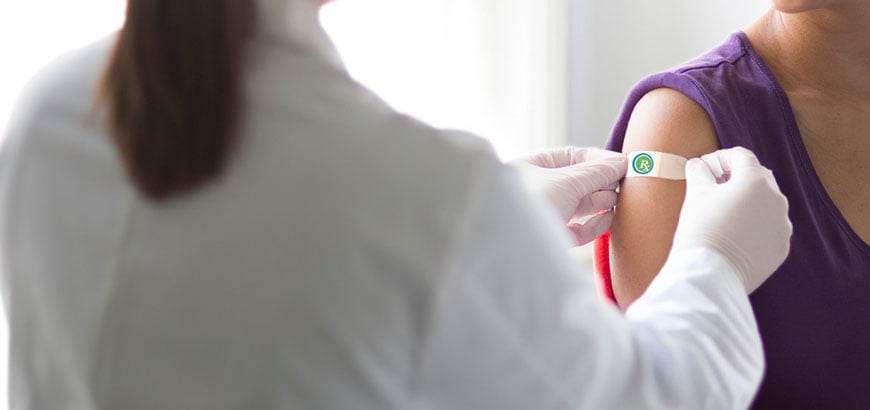 A pharmacist places a bandaid on a patients arm