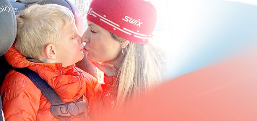 A mom kissing her small son sitting in a car seat