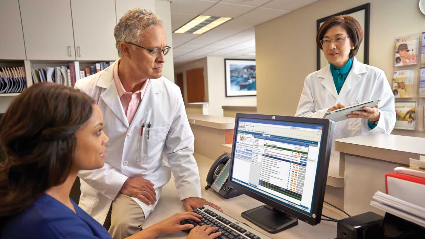 A doctor and nurses gather around a computer