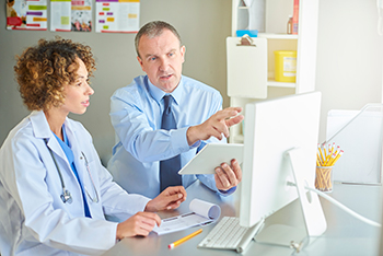 A doctor and hospital worker review information on a computer